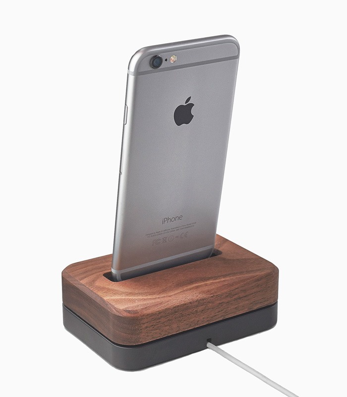 Серый iPhone 6 стоит на стильной деревянной подставке для зарядки.